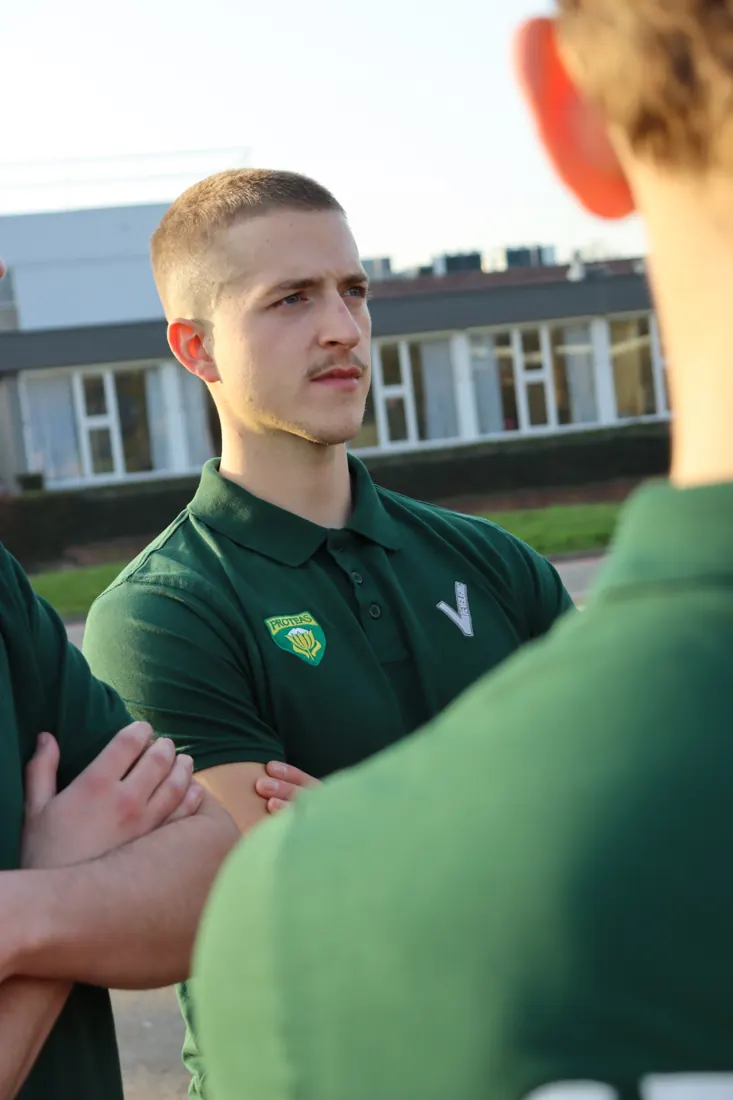 Evenementenbeveiliger van Proteas, alert met de armen over elkaar in de avondzon.