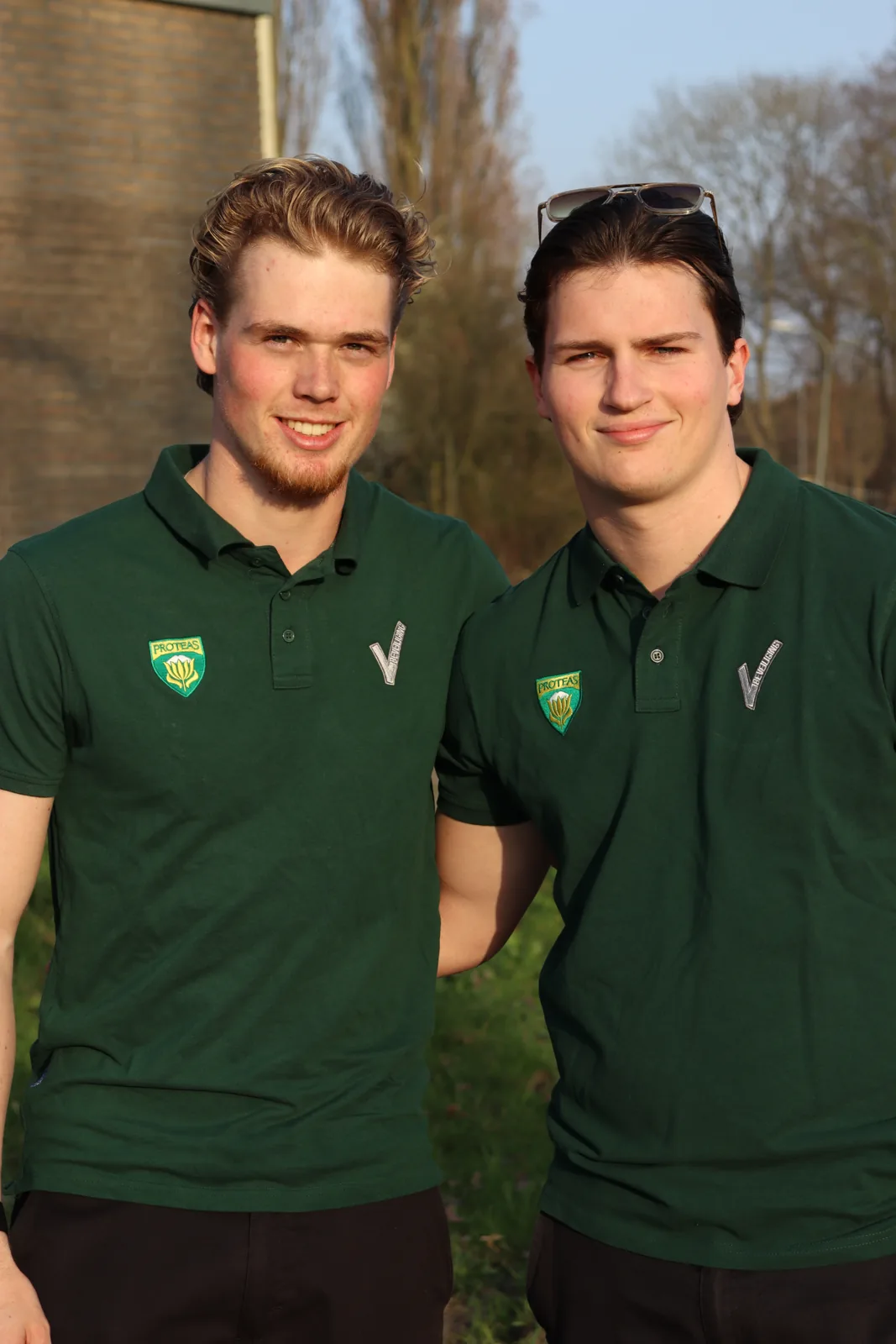 Twee lachende Proteas beveiligers in groene bedrijfspolo's bij de watertoren.